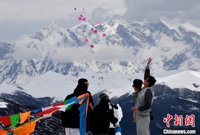 圖為5月14日，游客在西藏林芝色季拉山觀景臺(tái)拋灑“隆達(dá)”(風(fēng)馬旗，藏族民眾的一種祈福方式)?！±盍?攝